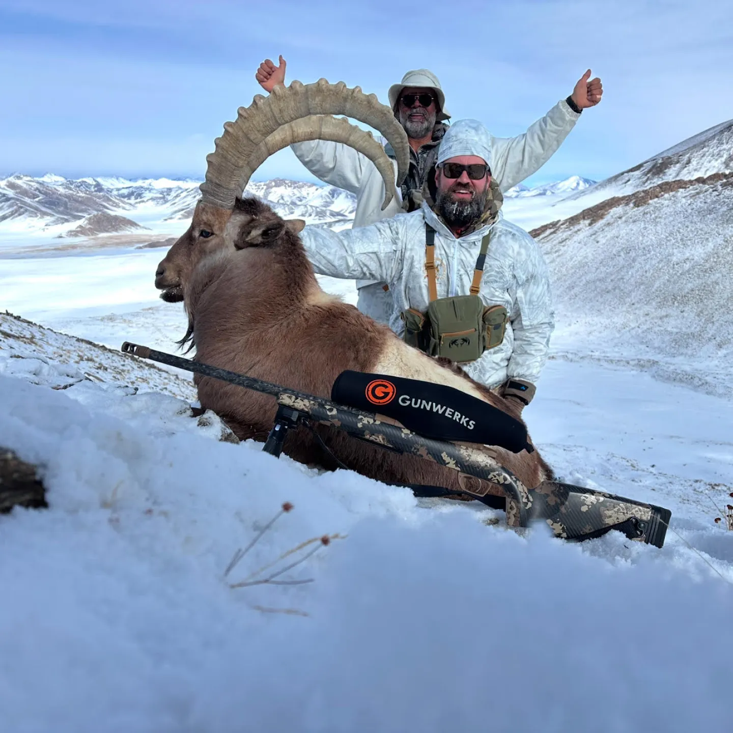 Two Gunwerks customers with a markhor in a snowy, mountainous landscape